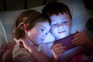 Kids having screen time in bed with cell phone